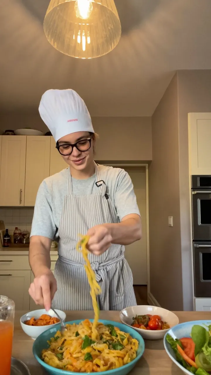 Food reel still: a cook tossing pasta in a home kitchen.