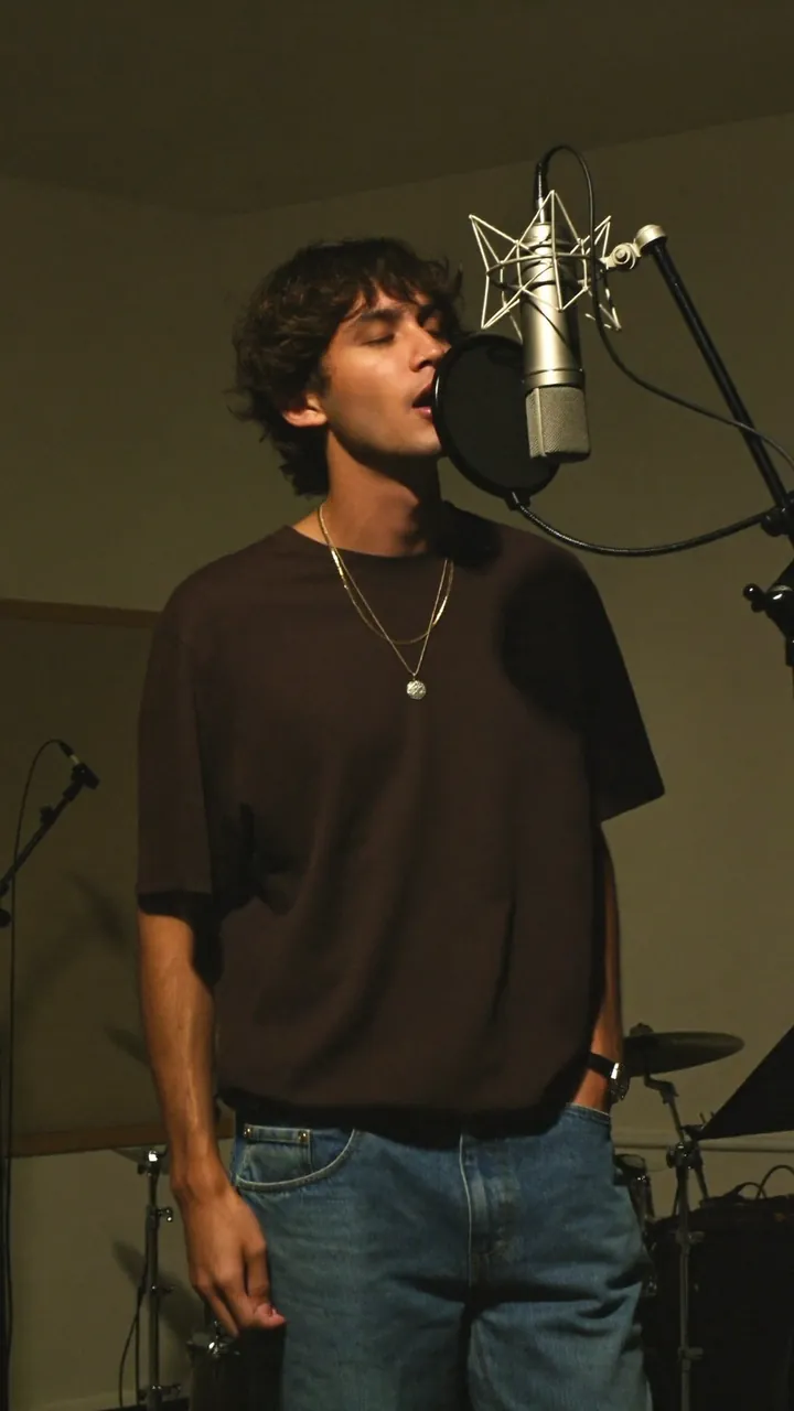 Music reel still: a singer at a studio microphone.
